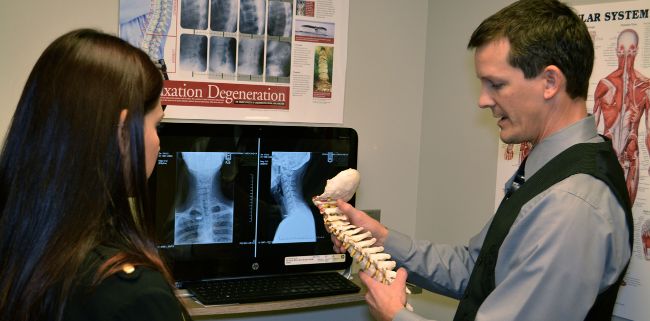 woman diagnosed neck injury discussing with chiropractor 